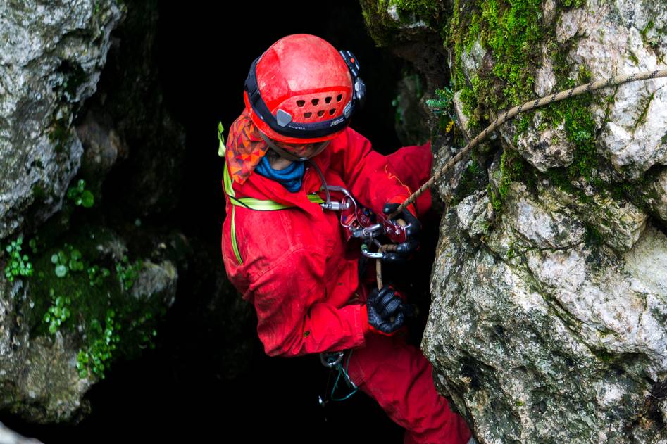 Climber wearing rugged leather gloves gripping rocky cliff