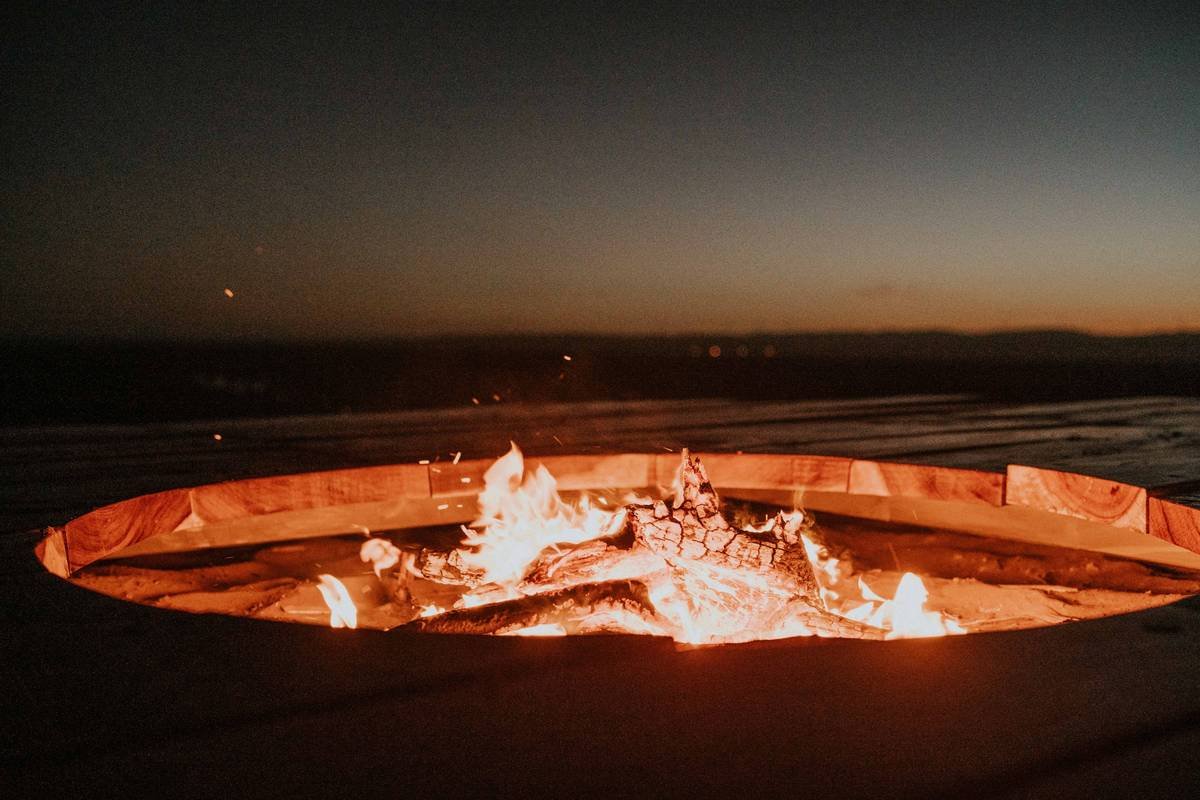 Infographic comparing open fire pit vs enclosed outdoor fire pit: shows 90% less ember escape, 40% better heat retention, and lower clearance requirements for enclosed model