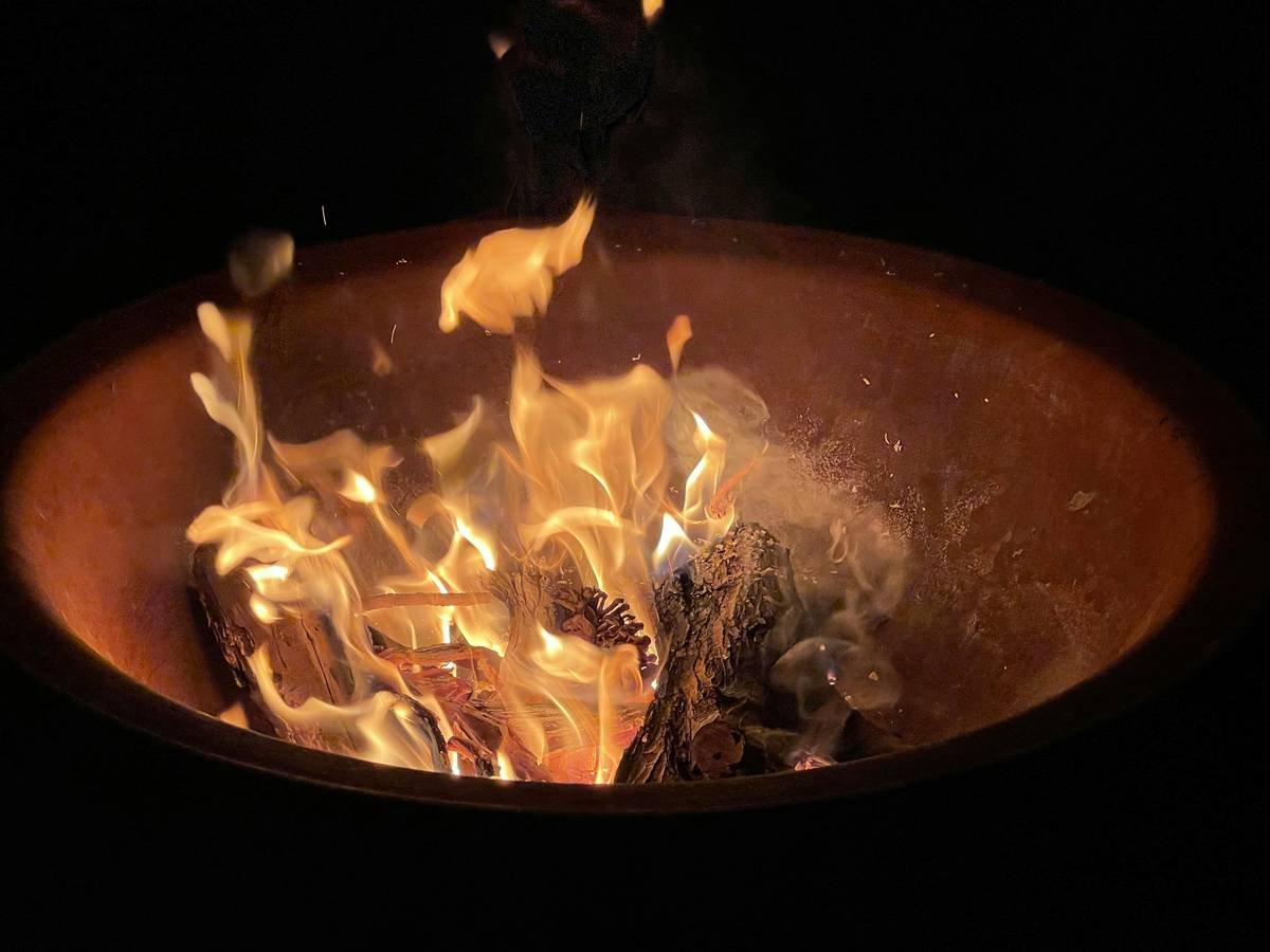 Photo showing warped HDPE wicker sectional next to a metal fire pit with residual ash and scorch marks on surrounding pavers.
