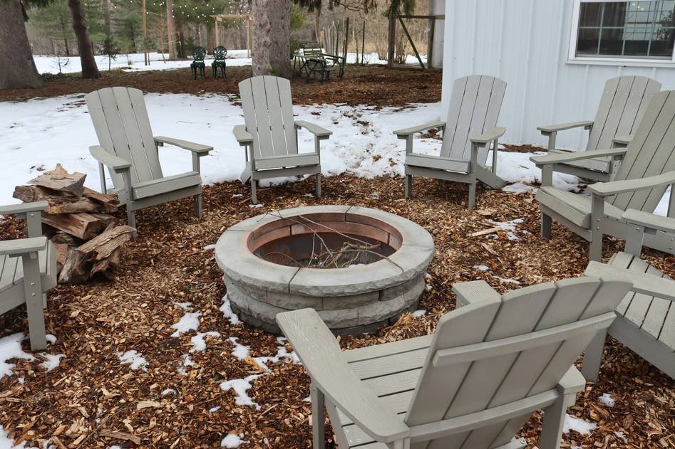 Rustic fire pit chairs arranged around a glowing outdoor fire
