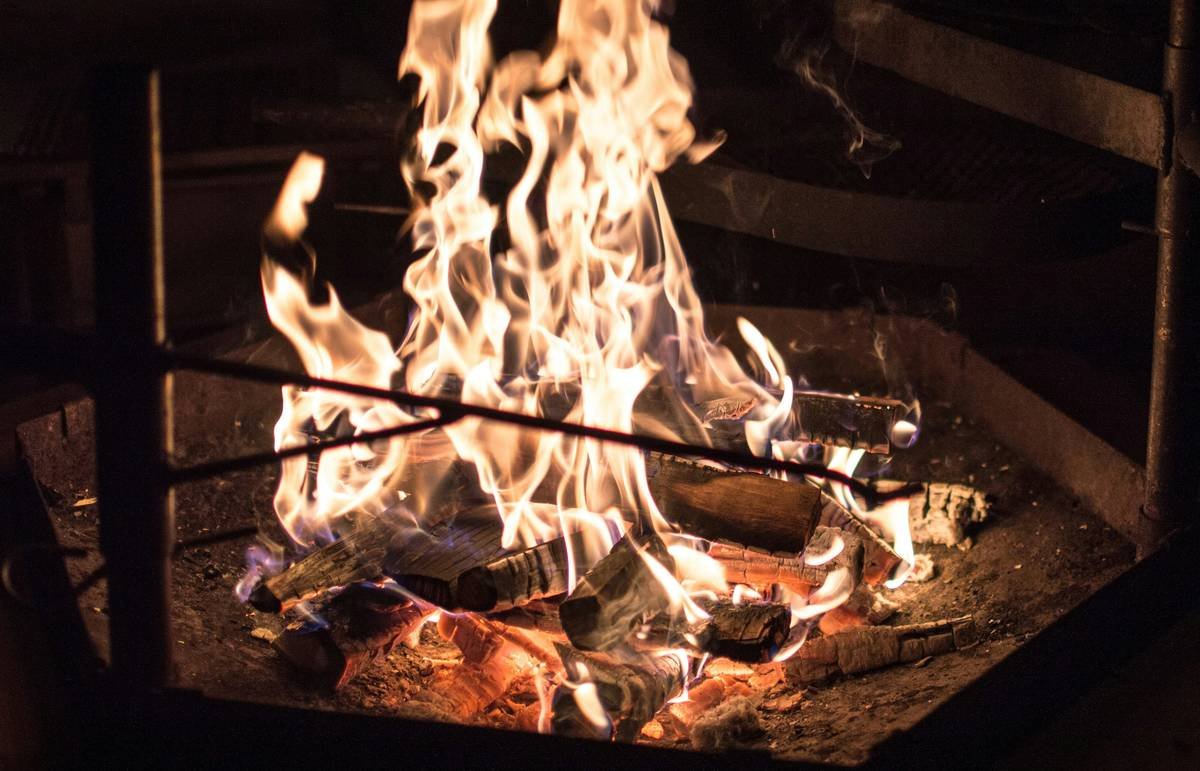Close-up of weather-resistant cushions and a woven blanket on fire pit seating demonstrating how to decorate a fire pit